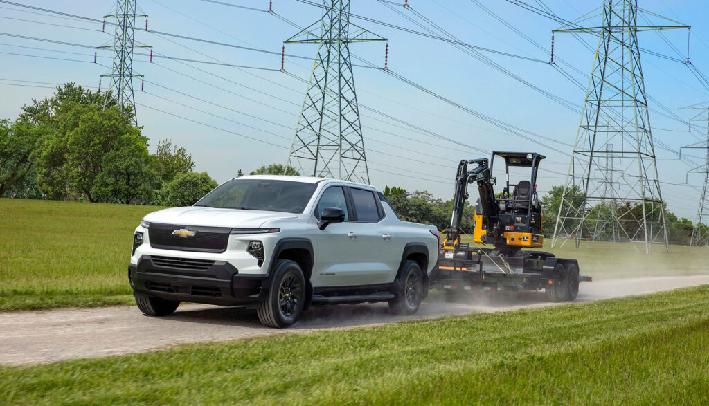 Photo of a Chevrolet Silverado EV pickup truck towing a small digger.