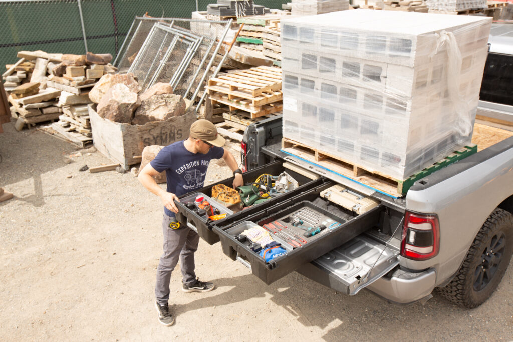 Image shows a contractor selecting a tool from a DECKED Drawer System mounted in a pickup truck flatbed.